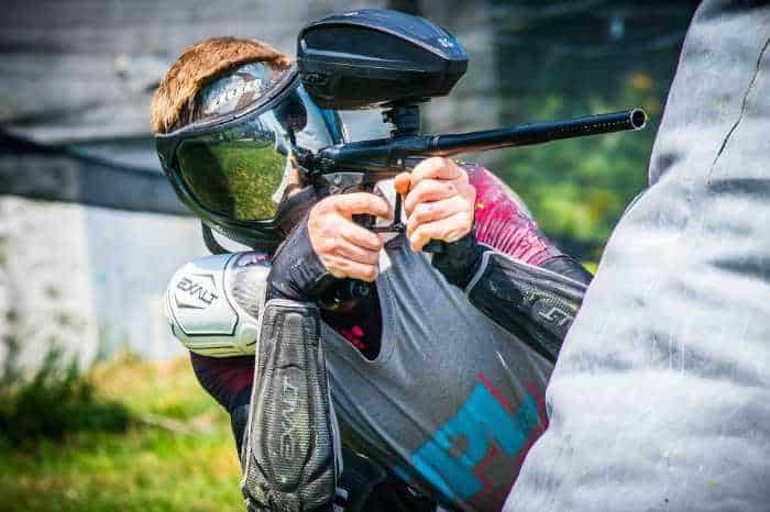 person playing paintball leaning out from cover